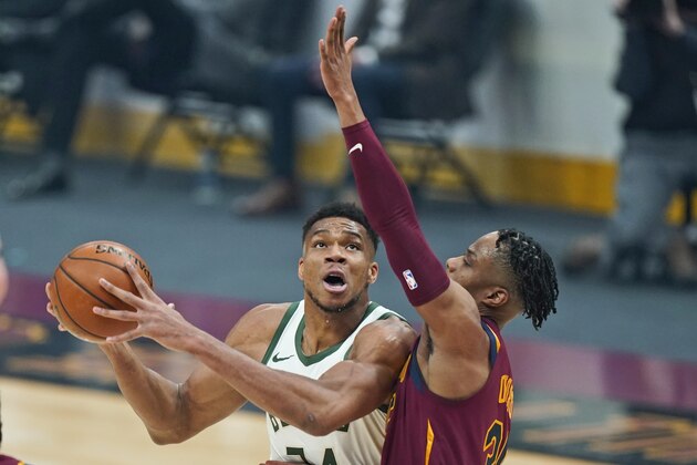 Milwaukee Bucks' Giannis Antetokounmpo, left, drives against Cleveland Cavaliers' Isaac Okoro in the first half of an NBA basketball game, Friday, Feb. 5, 2021, in Cleveland. (AP Photo/Tony Dejak)