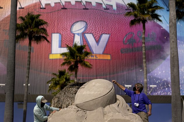 Workers sculpt the Lombardi Trophy out of sand outside of Raymond James Stadium ahead of Super Bowl 55 Thursday, Feb. 4, 2021, in Tampa, Fla. The city is hosting Sunday's Super Bowl football game between the Tampa Bay Buccaneers and the Kansas City Chiefs. (AP Photo/Charlie Riedel)