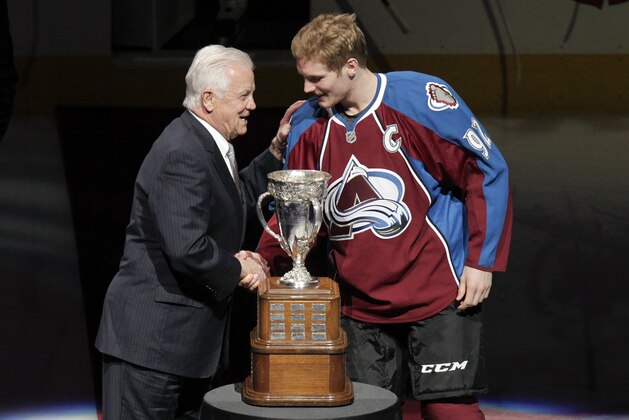 Former NHL player Ralph Backstrom, left, awards the Calder Trophy to Colorado Avalanche's Gabriel Landeskog, right, of Sweden, the 2012 NHL rookie of the year, before an NHL hockey between the Avalanche and the Los Angeles Kings on Tuesday, Jan. 22, 2013, in Denver. Backstrom won the award in 1959. (AP Photo/Barry Gutierrez)