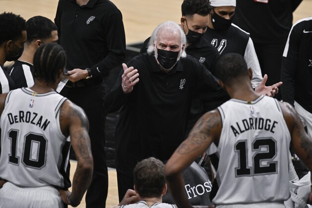 San Antonio Spurs head coach Gregg Popovich, center, talks to his players during a timeout in the second half of an NBA basketball game against the Memphis Grizzlies, Saturday, Jan. 30, 2021, in San Antonio. (AP Photo/Darren Abate)