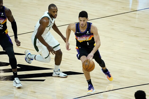 Phoenix Suns guard Devin Booker (1) drives as Milwaukee Bucks forward Khris Middleton defends during the first half of an NBA basketball game Wednesday, Feb. 10, 2021, in Phoenix. (AP Photo/Matt York) Phoenix Suns guard Devin Booker (1) drives as Milwaukee Bucks forward Khris Middleton defends during the first half of an NBA basketball game Wednesday, Feb. 10, 2021, in Phoenix. (AP Photo/Matt York)