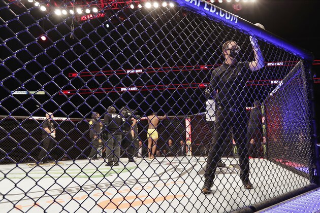 A worker wipes down the padding on the octagon between bouts during a UFC 249 mixed martial art event Saturday, May 9, 2020, in Jacksonville, Fla. (AP Photo/John Raoux)