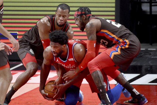 Philadelphia 76ers center Joel Embiid, center, scrambles for the ball against Portland Trail Blazers guard Rodney Hood, left, and forward Robert Covington during the first half of an NBA basketball game in Portland, Ore., Thursday, Feb. 11, 2021. (AP Photo/Steve Dykes)
