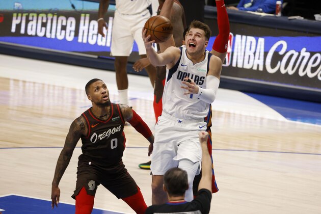 Portland Trail Blazers guard Damian Lillard (0) watches as Dallas Mavericks guard Luka Doncic (77) makes a basket as ande is fouled by center Enes Kanter during the first half of an NBA basketball game in Dallas, Sunday, Feb. 14, 2021. (AP Photo/Michael Ainsworth)