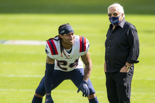 New England Patriots owner Robert Kraft wears a mask on the field as he talks with New England Patriots cornerback Stephon Gilmore (24) before the Patriots take on the Miami Dolphins during an NFL football game, Sunday, Dec. 20, 2020, in Miami Gardens, Fla. (AP Photo/Doug Murray)
