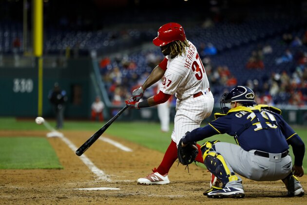 Philadelphia Phillies' Odubel Herrera, left, hits a two-run double off Milwaukee Brewers relief pitcher Junior Guerra during the seventh inning of a baseball game, Monday, May 13, 2019, in Philadelphia. At right is Brewers catcher Yasmani Grandal. Philadelphia won 7-4. (AP Photo/Matt Slocum)