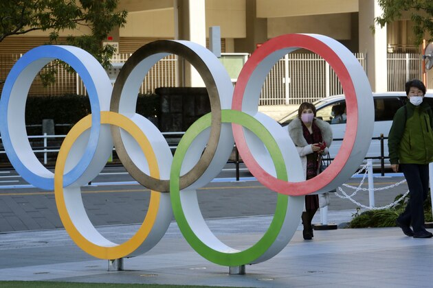 People walk past the Olympic rings in Tokyo Tuesday, Feb. 2, 2021. Pressure is building on Japanese organizers and the IOC to explain exactly how they plan to hold the Tokyo Olympics in the midst of a pandemic. (AP Photo/Koji Sasahara)