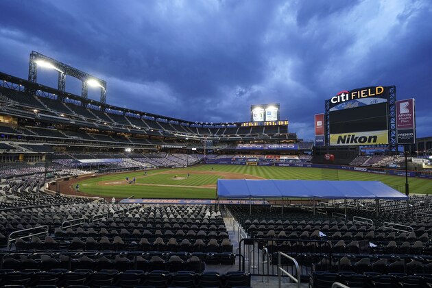 Members of the grounds crew close the field as the lights are turned down at Citi Field after the New York Mets and Miami Marlins walked before a baseball game Thursday, Aug. 27, 2020, in New York. Players jointly walked off the field after a moment of silence, draping a Black Lives Matter T-shirt across home plate as they chose not to play. (AP Photo/John Minchillo)