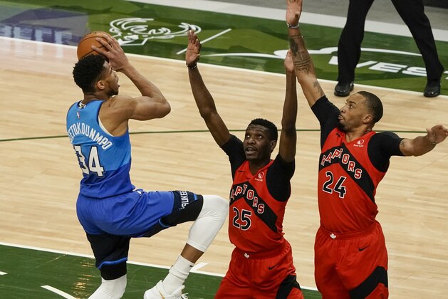 Milwaukee Bucks' Giannis Antetokounmpo shoots over Toronto Raptors' Chris Boucher (25) and Norman Powell (24) during the first half of an NBA basketball game Thursday, Feb. 18, 2021, in Milwaukee. (AP Photo/Morry Gash)