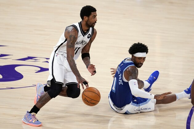 Brooklyn Nets guard Kyrie Irving, left, dribbles past Los Angeles Lakers guard Kentavious Caldwell-Pope during the first half of an NBA basketball game Thursday, Feb. 18, 2021, in Los Angeles. (AP Photo/Marcio Jose Sanchez)
