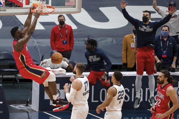 New Orleans Pelicans forward Zion Williamson (1) dunks next to Memphis Grizzlies center Jonas Valanciunas (17) and guard Desmond Bane (22) during the fourth quarter of an NBA basketball game in New Orleans, Saturday, Feb. 6, 2021. (AP Photo/Derick Hingle)