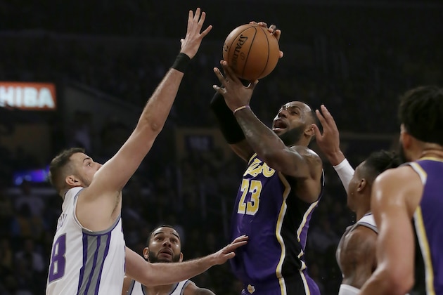 Los Angeles Lakers forward LeBron James, center, drives to the basket against Sacramento Kings forward Nemanja Bjelica, left, forward Richaun Holmes, right, and guard Cory Joseph (9) during the first half of an NBA basketball game in Los Angeles, Friday, Nov. 15, 2019. (AP Photo/Alex Gallardo)