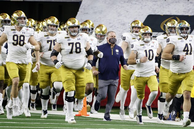 Notre Dame head coach Brian Kelly, center, jogs onto the field alongside his team for at the start of the Rose Bowl NCAA college football game against Alabama in Arlington, Texas, Friday, Jan. 1, 2021. (AP Photo/Ron Jenkins)
