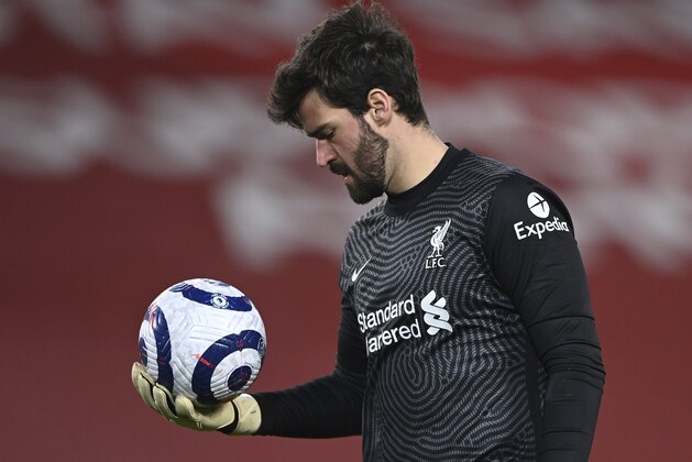 Liverpool's goalkeeper Alisson looks down at the ball during the English Premier League soccer match between Liverpool and Everton at Anfield in Liverpool, England, Saturday, Feb. 20, 2021. Everton won the game 2-0. (Lawrence Griffiths/ Pool via AP)