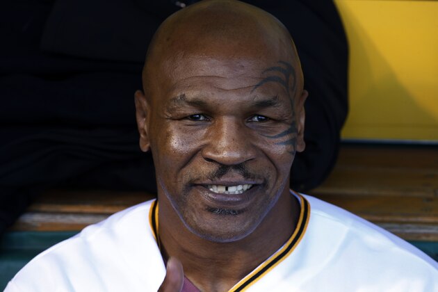 Former boxing heavyweight champion Mike Tyson sits in the Pittsburgh Pirates dugout as he waits to throw out the first pitch before  a baseball game between the Pittsburgh Pirates and the Milwaukee Brewers in Pittsburgh Thursday, April 17, 2014. (AP Photo/Gene J. Puskar)