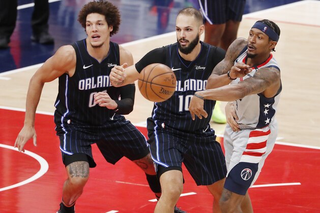 Washington Wizards guard Bradley Beal, right, passes the ball in front of Orlando Magic forward Aaron Gordon, left, and guard Evan Fournier, center, in the third quarter of an NBA basketball game Sunday, Dec. 27, 2020, in Washington. (Shawn Thew/Pool Photo via AP)