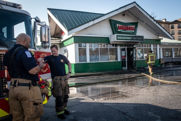 Firefighters talk in front of a burned Krispy Kreme Doughnuts store in Atlanta on Wednesday, Feb. 10, 2021. The historic store was engulfed in flames early Wednesday. The store owned by Basketball Hall-of-Famer Shaquille O'Neal was significantly damaged. (AP Photo/Ron Harris)