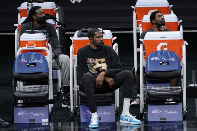 Brooklyn Nets DeAndre Jordan, left, Kevin Durant, center, and Kyrie Irving watch their teammates play the Sacramento King during the second half of an NBA basketball game in Sacramento, Calif., Monday, Feb. 15, 2021. Durant did not play due to an injury. The Nets won 136-125. (AP Photo/Rich Pedroncelli)