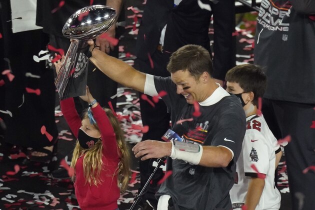 Tampa Bay Buccaneers quarterback Tom Brady, with member of his family, holds the Super Bowl trophy as he celebrates the team's win over the Kansas City Chiefs in the NFL Super Bowl 55 football game Sunday, Feb. 7, 2021, in Tampa, Fla. The Buccaneers defeated the Chiefs 31-9 to win the Super Bowl. (AP Photo/Charlie Riedel)