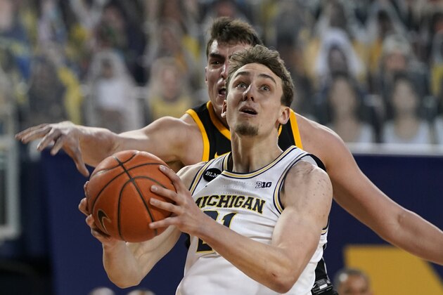 Michigan guard Franz Wagner (21) makes a layup as Iowa center Luka Garza defends during the second half of an NCAA college basketball game, Thursday, Feb. 25, 2021, in Ann Arbor, Mich. (AP Photo/Carlos Osorio)