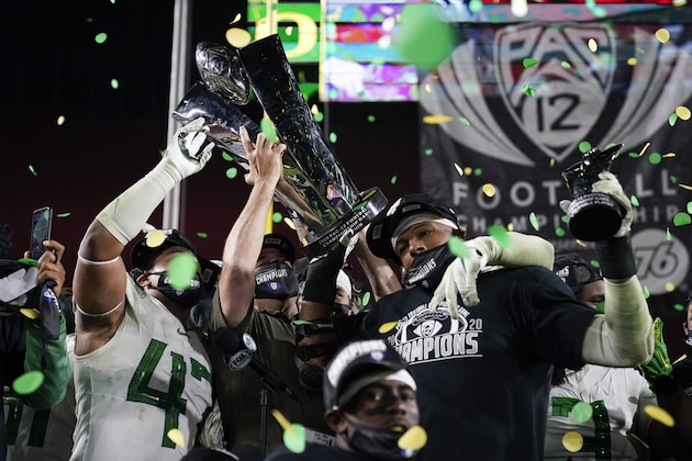 Oregon head coach Mario Cristobal, center, and defensive end Kayvon Thibodeaux, right, present their championship trophy and MVP trophy after winning the NCAA college football game for the Pac-12 Conference championship Friday, Dec 18, 2020, in Los Angeles. Oregon won 31-24. (AP Photo/Ashley Landis)