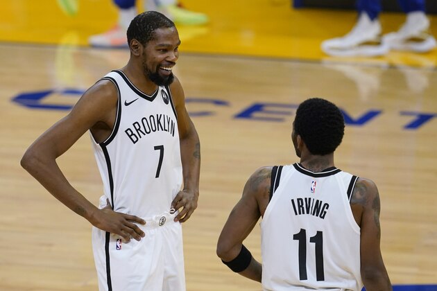 Brooklyn Nets forward Kevin Durant (7) smiles while talking with guard Kyrie Irving (11) before the team's NBA basketball game against the Golden State Warriors in San Francisco, Saturday, Feb. 13, 2021. (AP Photo/Jeff Chiu)