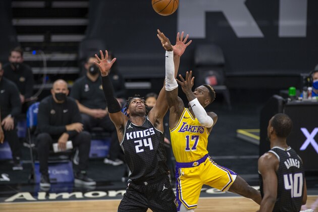 Sacramento Kings guard Buddy Hield (24) defends Los Angeles Lakers guard Dennis Schroder (17) during the first quarter of an NBA basketball game in Sacramento, Calif., Wednesday, March 3, 2021. (AP Photo/Hector Amezcua)