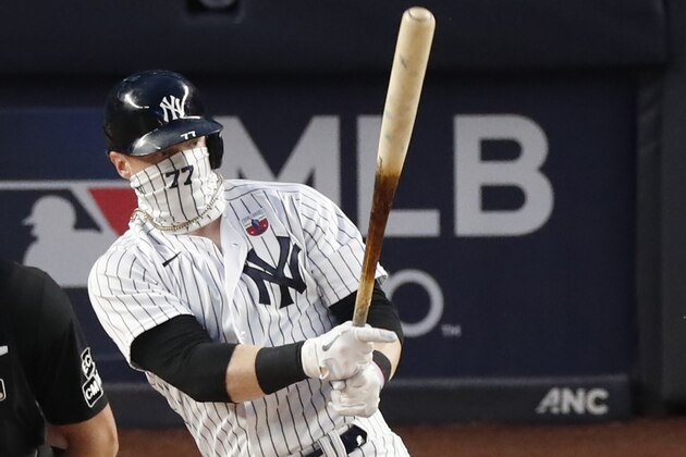 New York Yankees designated hitter Clint Frazier bats during the team's baseball game against the Boston Red Sox, Sunday, Aug. 16, 2020, in New York. Frazier is hitting .571 with two homers and eight RBIs in four games since rejoining the Yankees. He is distinctive not for his red hair that used to be long but for a team-logo gaiter that covers nearly his entire face. (AP Photo/Kathy Willens)