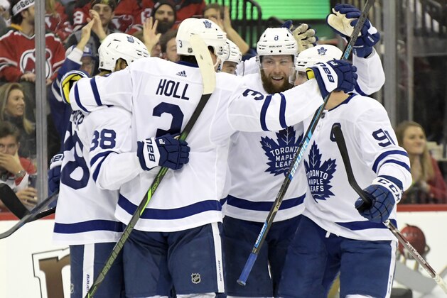 Toronto Maple Leafs' William Nylander (88), Justin Holl (3), Jake Muzzin (8) and John Tavares (91) surround Ilya Mikheyev to celebrate his goal during the first period of an NHL hockey game against the New Jersey Devils, Friday, Dec. 27, 2019, in Newark, N.J. (AP Photo/Bill Kostroun)