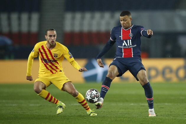 PSG's Kylian Mbappe, right, is challenged by Barcelona's Oscar Mingueza during the Champions League, round of 16, second leg soccer match between Paris Saint-Germain and FC Barcelona at the Parc des Princes stadium in Paris, Wednesday, March 10, 2021. (AP Photo/Christophe Ena)