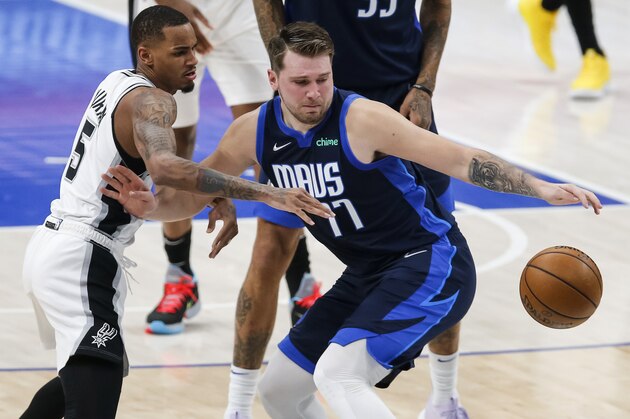 Dallas Mavericks guard Luka Doncic (77) reaches for the ball, while fending off San Antonio Spurs guard Dejounte Murray (5) during the first half of an NBA basketball game Wednesday, March 10, 2021, in Dallas. (AP Photo/Brandon Wade)