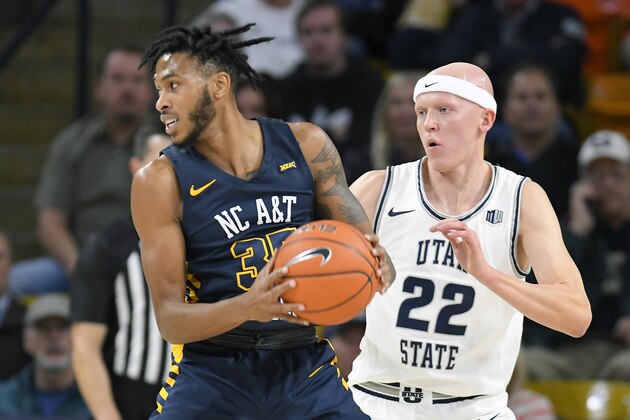 North Carolina A&T forward Tyrone Lyons (35) looks to pass the ball as Utah State guard Brock Miller (22) defends during the first half of an NCAA college basketball game Friday, Nov. 15, 2019, in Logan, Utah. (AP Photo/Eli Lucero)
