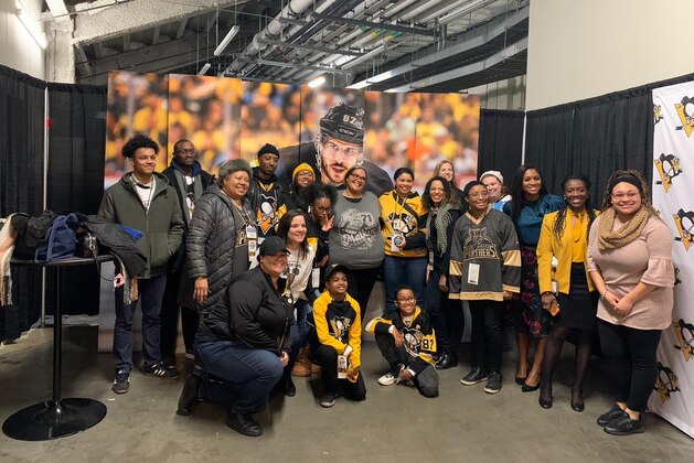 FILE - In this Feb. 15, 2020, file photo, fans pose below the NHL league logo at a display outside Falcon Stadium before an NHL Stadium Series outdoor hockey game between the Los Angeles Kings and Colorado Avalanche, at Air Force Academy, Colo. The uncertainty raised by coronavirus pandemic leads to experts providing a bleak short-term assessment on the NHL's financial bottom line, with some projecting revenues being cut by almost half. What's unclear is how large the impact might be until it can be determined when fans can resume attending games and if the league is able to complete this season. (AP Photo/David Zalubowski, File)