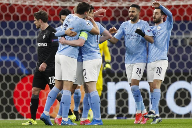 Manchester City's Kevin De Bruyne, obscured, is congratulated by teammates after scoring his team's first goal during the Champions League round of 16 second leg soccer match between Manchester City and Borussia Moenchengladbach at the Puskas Arena in Budapest, Hungary, Tuesday, March 16, 2021. (AP Photo/Laszlo Balogh)