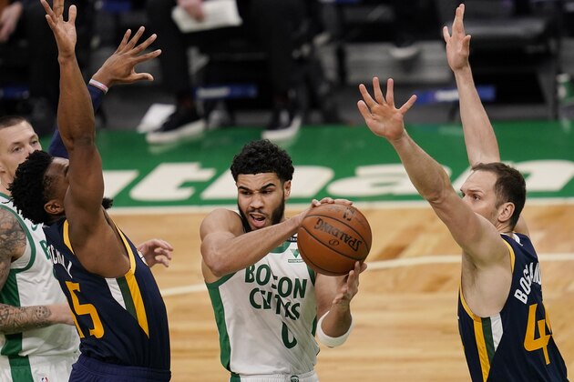 Boston Celtics forward Jayson Tatum, center, looks to pass the ball while pressured by Utah Jazz center Donovan Mitchell, left, and forward Bojan Bogdanovic, right, during the first half of an NBA basketball game, Tuesday, March 16, 2021, in Boston. (AP Photo/Charles Krupa)