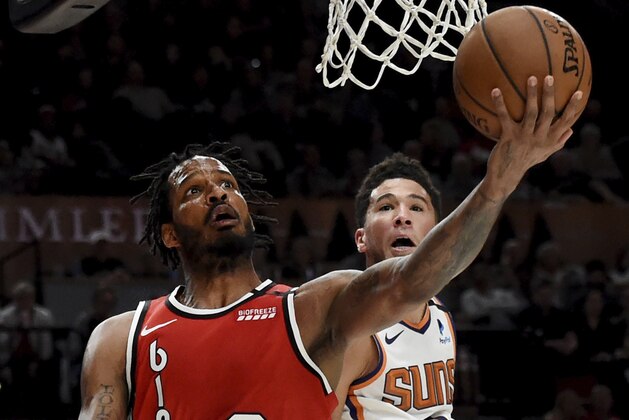 Portland Trail Blazers forward Trevor Ariza drives to the basket as Phoenix Suns guard Devin Booker defends during the second half of an NBA basketball game in Portland, Ore., Tuesday, March 10, 2020. The Blazers won 121-105. (AP Photo/Steve Dykes)