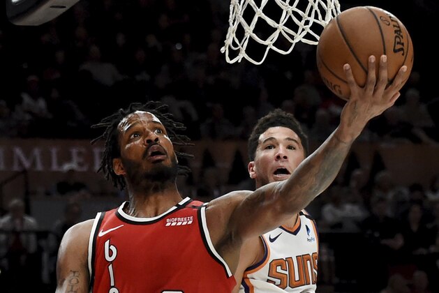 Portland Trail Blazers forward Trevor Ariza drives to the basket as Phoenix Suns guard Devin Booker defends during the second half of an NBA basketball game in Portland, Ore., Tuesday, March 10, 2020. The Blazers won 121-105. (AP Photo/Steve Dykes)