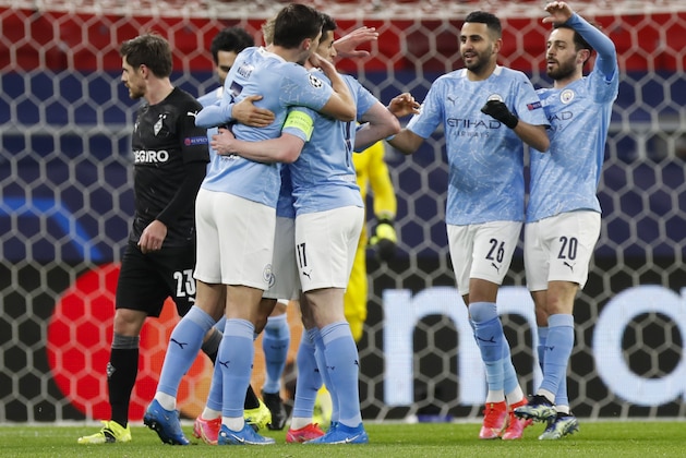 Manchester City's Kevin De Bruyne, obscured, is congratulated by teammates after scoring his team's first goal during the Champions League round of 16 second leg soccer match between Manchester City and Borussia Moenchengladbach at the Puskas Arena in Budapest, Hungary, Tuesday, March 16, 2021. (AP Photo/Laszlo Balogh)