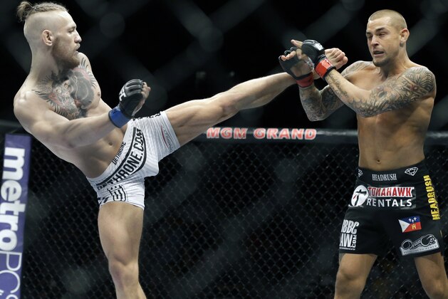 FILE - This Sept. 27, 2014, file photo shows Conor McGregor, left, kicking at Dustin Poirier, during their fight in Las Vegas. The UFC is surging toward the end of the year by flexing its promotional muscles for three straight nights in Vegas.  McGregor’s featherweight title showdown with champion Jose Aldo is only the culmination of a three-day fight extravaganza this weekend. (AP Photo/John Locher,File)
