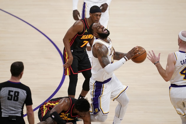 Los Angeles Lakers forward LeBron James, center, grimaces as he trips and injures himself over Atlanta Hawks forward Tony Snell, bottom, during the first half of an NBA basketball game Saturday, March 20, 2021, in Los Angeles. (AP Photo/Marcio Jose Sanchez)