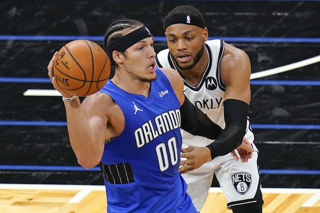 Orlando Magic forward Aaron Gordon (00) passes the ball as Brooklyn Nets forward Bruce Brown, right, guards him during the first half of an NBA basketball game, Friday, March 19, 2021, in Orlando, Fla. (AP Photo/John Raoux)