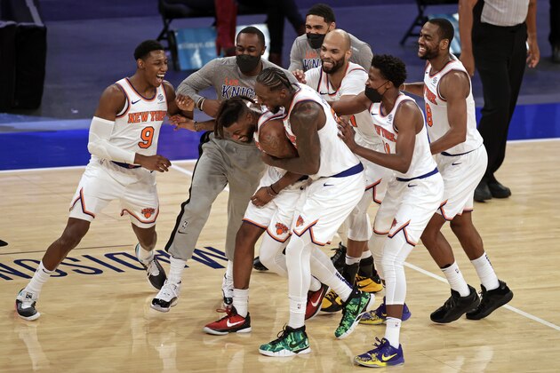 New York Knicks forward Reggie Bullock is mobbed by teammates after taking the ball away from the Orlando Magic in the final seconds of an NBA basketball game Thursday, March 18, 2021, in New York. The Knicks won 94-93. (AP Photo/Adam Hunger, Pool)