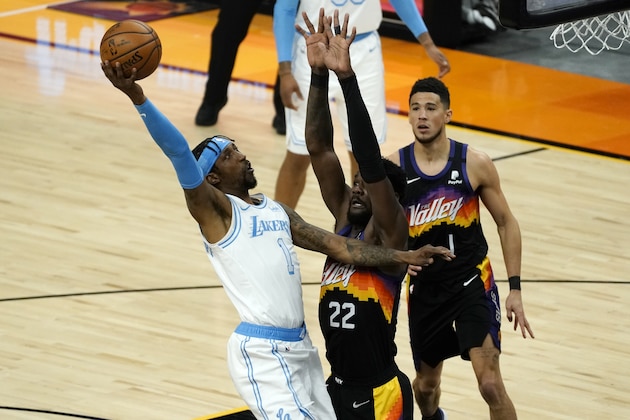 Los Angeles Lakers guard Kentavious Caldwell-Pope (1) drives past Phoenix Suns center Deandre Ayton (22) and guard Devin Booker (1) during the first half of an NBA basketball game, Sunday, March 21, 2021, in Phoenix. (AP Photo/Rick Scuteri)