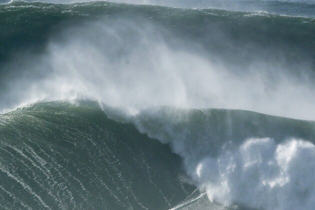 A surfer rides a wave during a tow surfing session at Praia do Norte or North Beach in Nazare, Portugal, Thursday, Oct. 29, 2020. A big swell generated earlier in the week by Hurricane Epsilon in the North Atlantic, reached the Portuguese west coast drawing big wave surfers to Nazare. (AP Photo/Pedro Rocha)