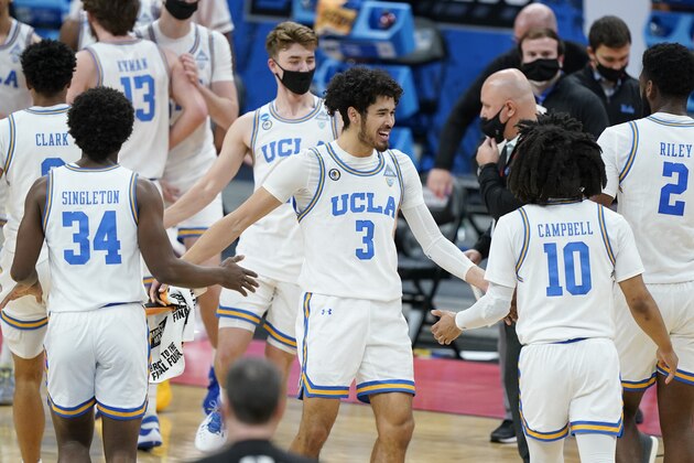 UCLA's Johnny Juzang (3) congratulates David Singleton (34) and Tyger Campbell (10) during a timeout in the first half of a college basketball game against Abilene Christian in the second round of the NCAA tournament at Bankers Life Fieldhouse in Indianapolis Monday, March 22, 2021. (AP Photo/Mark Humphrey)