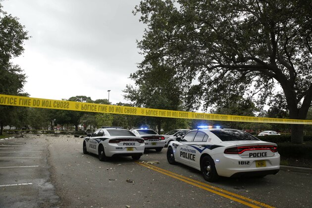 Police vehicles are behind police tape after an explosion at a shopping plaza on Saturday, July 6, 2019, in Plantation, Fla.  Several people were injured after a vacant pizza restaurant exploded in the South Florida shopping plaza Saturday, according to police.  The restaurant was destroyed, and nearby businesses were damaged. (AP Photo/Brynn Anderson)