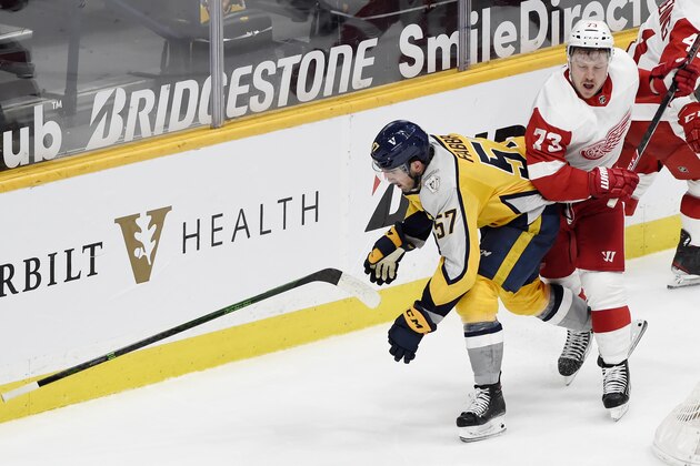 Nashville Predators defenseman Dante Fabbro (57) drops his stick after being checked from behind by Detroit Red Wings left wing Adam Erne (73) during the third period of an NHL hockey game Tuesday, March 23, 2021, in Nashville, Tenn. The Predators won 2-0. (AP Photo/Mark Zaleski)