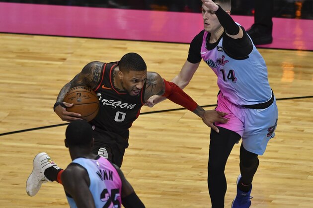 Portland Trail Blazers guard Damian Lillard (0) looks for space between Miami Heat guard Tyler Herro (14) and guard Kendrick Nunn (25) during the first half of an NBA basketball game, Thursday, March 25, 2021, in Miami. (AP Photo/Jim Rassol)