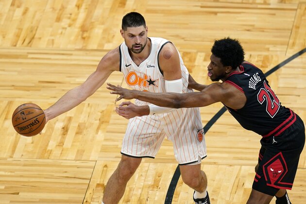 Orlando Magic center Nikola Vucevic, left, passes the ball around Chicago Bulls forward Thaddeus Young during the first half of an NBA basketball game Friday, Feb. 5, 2021, in Orlando, Fla. (AP Photo/John Raoux)