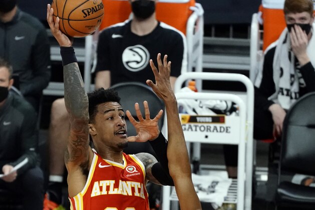 Atlanta Hawks forward John Collins (20) shoots over Phoenix Suns forward Mikal Bridges during the first half of an NBA basketball game Tuesday, March 30, 2021, in Phoenix. (AP Photo/Rick Scuteri)